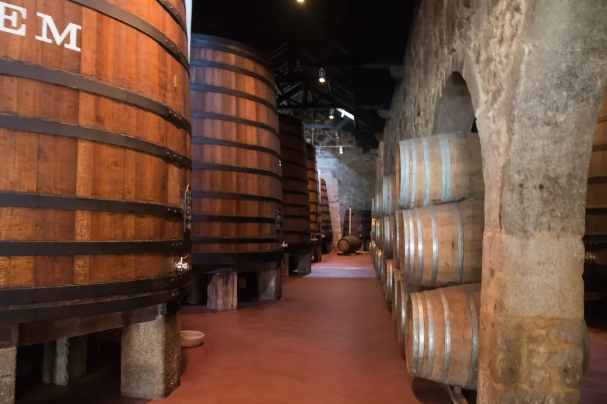 Oak vats and casks under the stone arches of the Cálem cellars in Vila Nova de Gaia, seen on Porto wine cellar tours