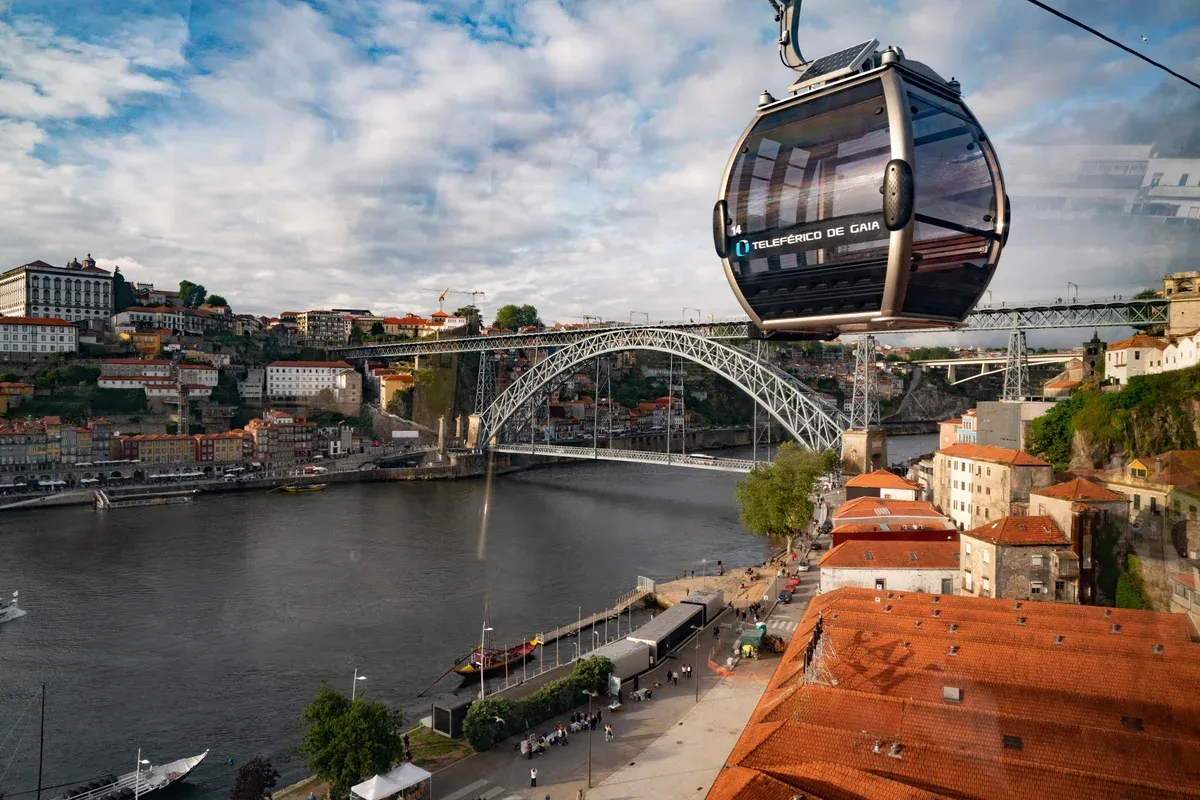 A Gaia Cable Car cabin above the lodge roofs, with the Ponte Luís I and Ribeira behind, seen on Porto wine cellar tours
