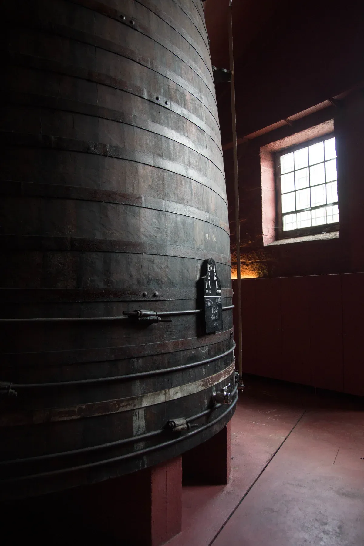 A tall port cask beside a cellar window in Vila Nova de Gaia, seen on a port wine cellar tour in Vila Nova de Gaia