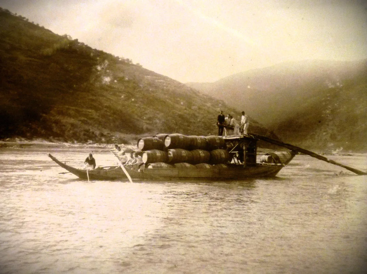 An old photograph of a rabelo boat carrying port barrels on the Douro, seen on a port wine cellar tour in Vila Nova de Gaia